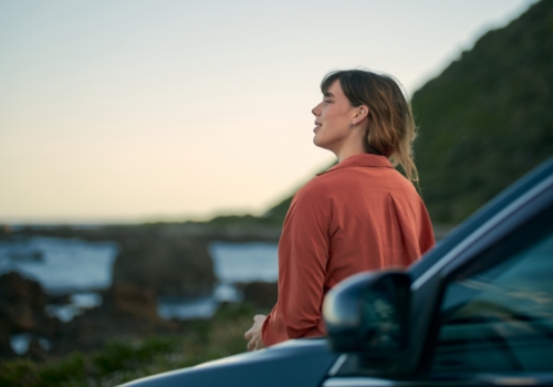 mulher feliz com o carro alugado