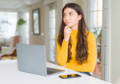 Young woman undecided with computer 