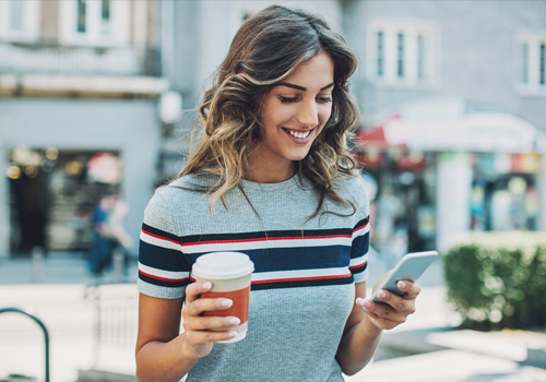 Mulher jovem a sorrir com telemóvel na mão