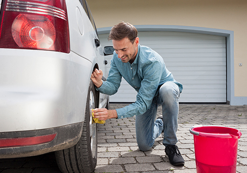 Man cleaning the rims of his car.